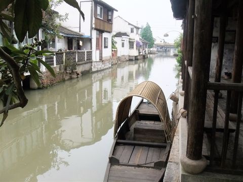 A traditional boat in a residential area canal.