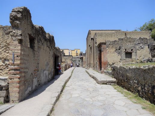 Decumano inferiore seen from its intersection with Cardo V.  On the right one can see the red brick portal of the House with large Portal.  The door just opposite the portal Leads to the Taberna Vasaria.