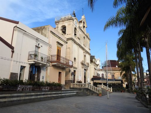 The church of San Giovanni Battista.  The two-storey old building at the righ end is the “Casa dei Pescatori di Aci Trezza”.