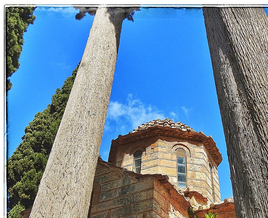 The dome of the catholicon behind two huge cypress trees.