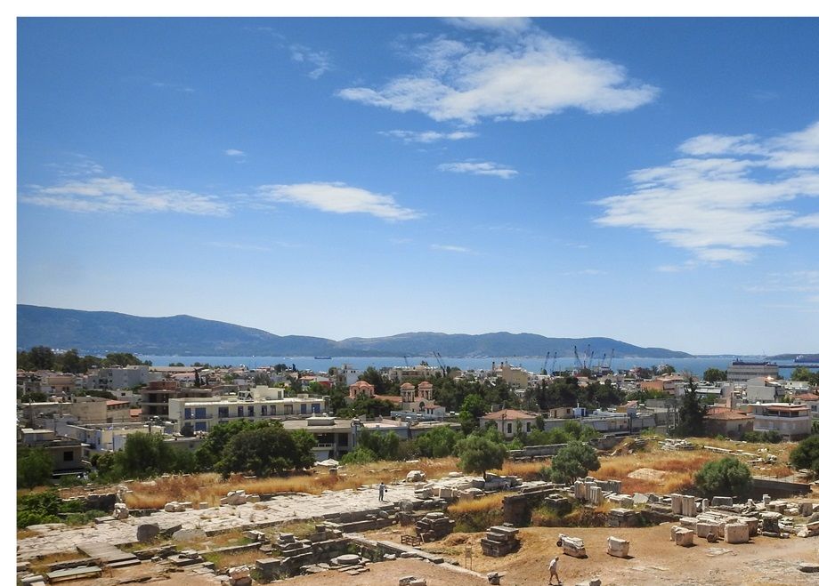Overall view of the eastern part of the Telesterion from the Rock Terrace. The paved corridor seen on the left is the portico of Philo added later to the Telesterion. The modern city of Eleusis can be seen at the background.