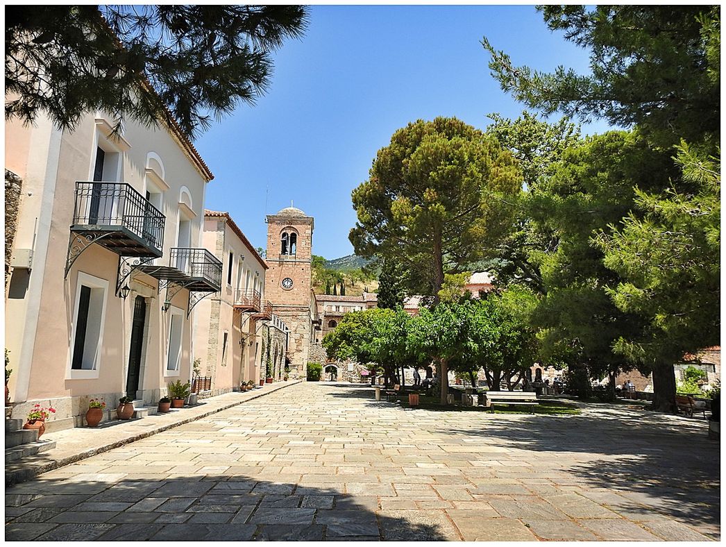 The shady courtyard outside the walls. At the background stands the clock tower next to the main (south) gate to the monastery.