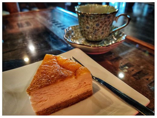 Coffee served into beautiful china and a delicious piece of cheesecake: typical serving in a traditional cafe.