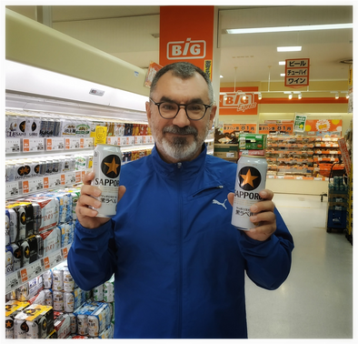 Me with two cans of Sapporo beer in a supermarket.