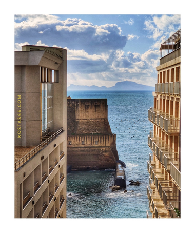 Castel dell' Ovo seen between two buildings at the foothills of Pizzofalcone hill.