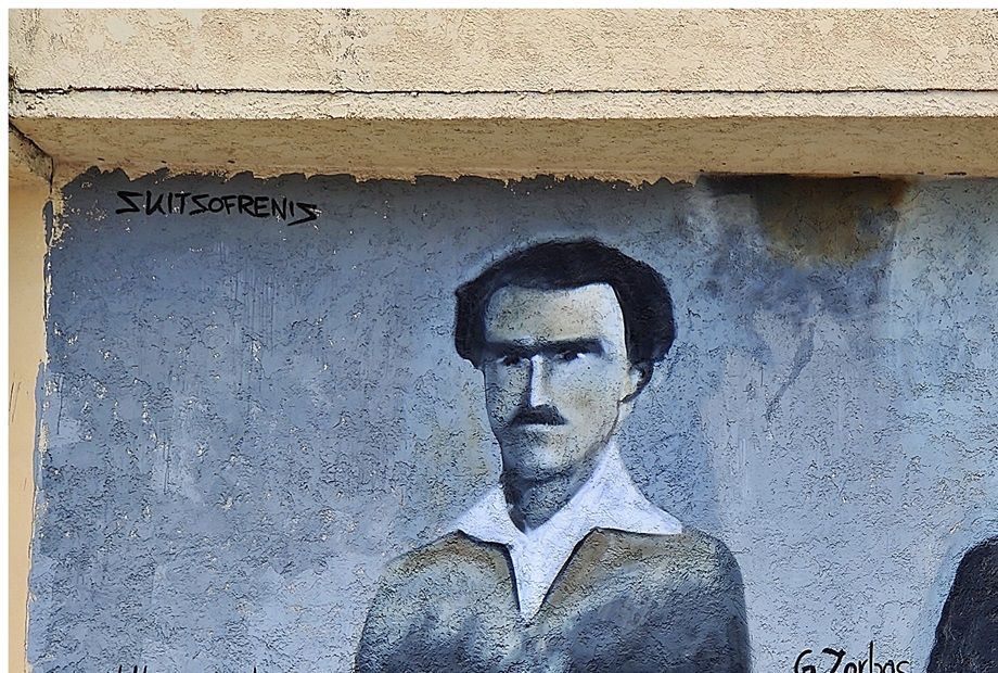 A wall painting of Kazantzakis and Zorbas at a sidewall of a house at Kalogria Beach.