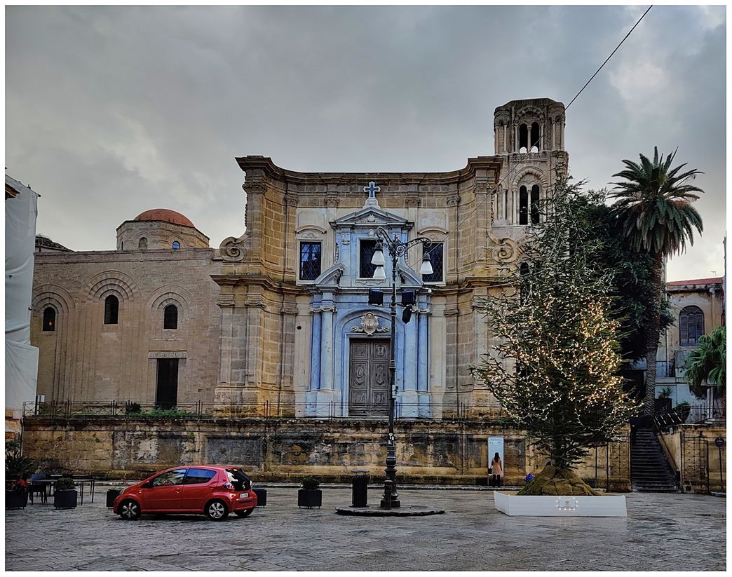 The north facade of Santa Maria dell'Ammiraglio on Piazza Bellini. The original church can be seen on the left, while the newer structure with the blueish Baroque façade and the campanile is seen on the right.