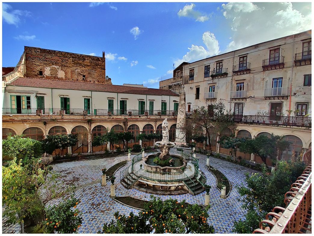 In the middle of the cloister stands the 18th-century fountain by Sicilian sculptor Ignazio Marabitti. You can see an obelisk (water tower) with the Dominican symbols in the corner behind the fountain.